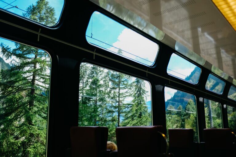 Panoramic train windows framing forests and mountains on a scenic rail journey in Europe