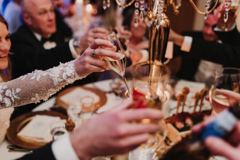 Wedding guests raising their glasses in a toast at a celebration dinner