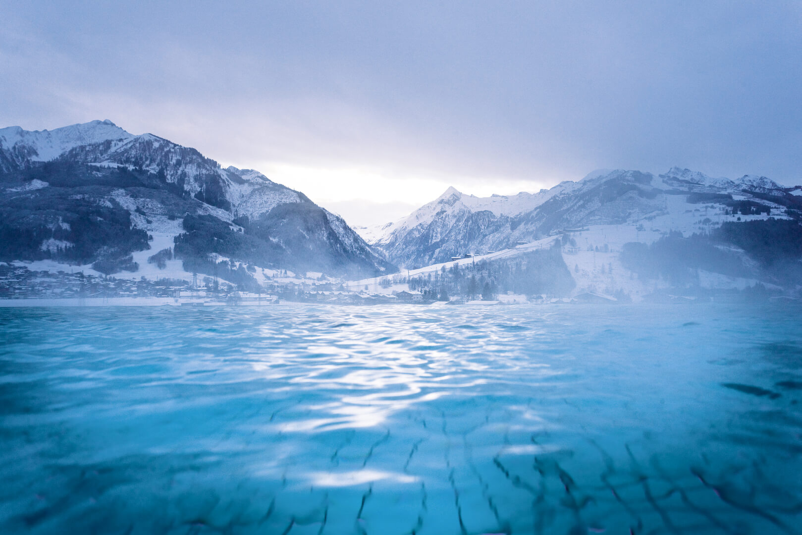Steaming outdoor pool with snowy mountains at the Tauern Spa in Kaprun