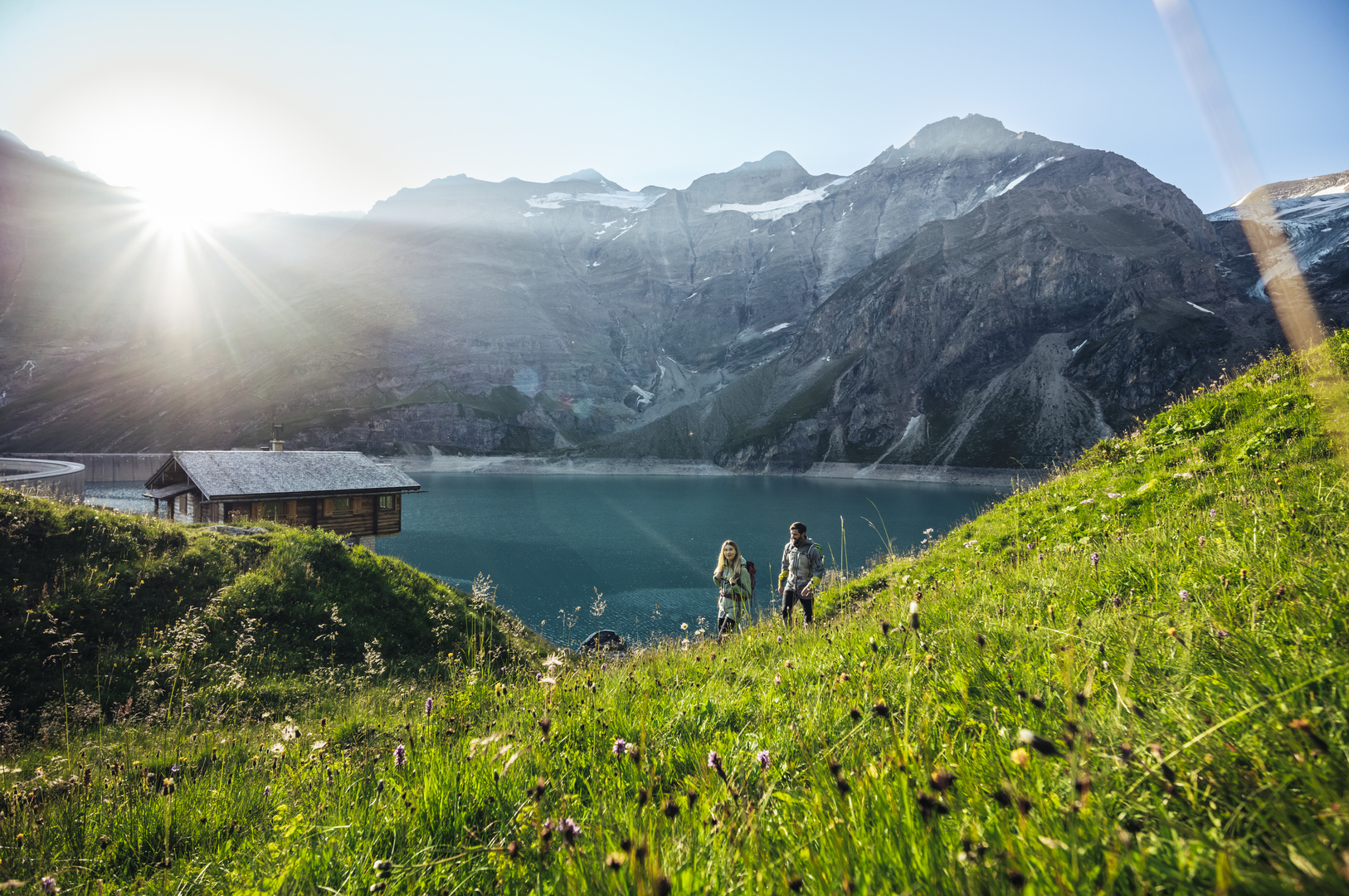 Hikers above the turquoise high mountain reservoirs in Kaprun