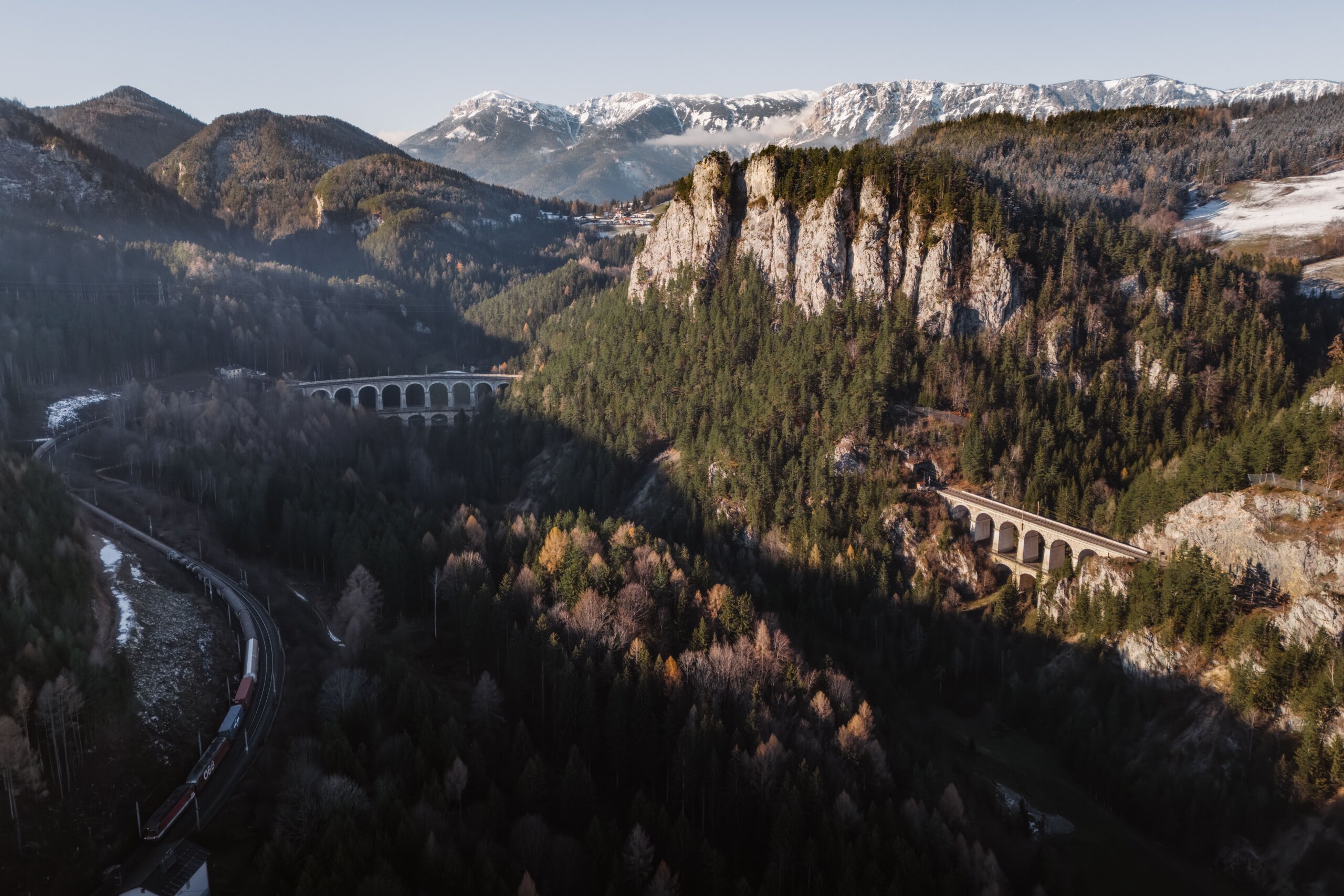 Stone viaducts of the Semmering Railway below the Polleroswand cliffs, with a train in the valley