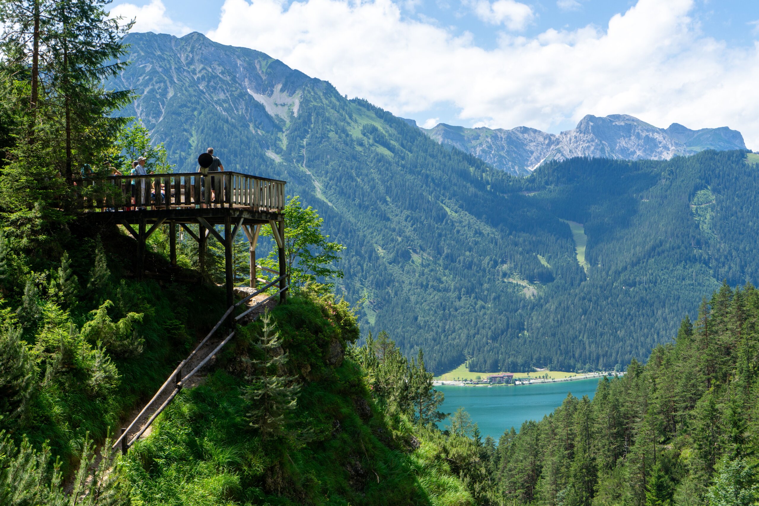 Hikers on a wooden viewing platform above the turquoise Achensee in Tyrol