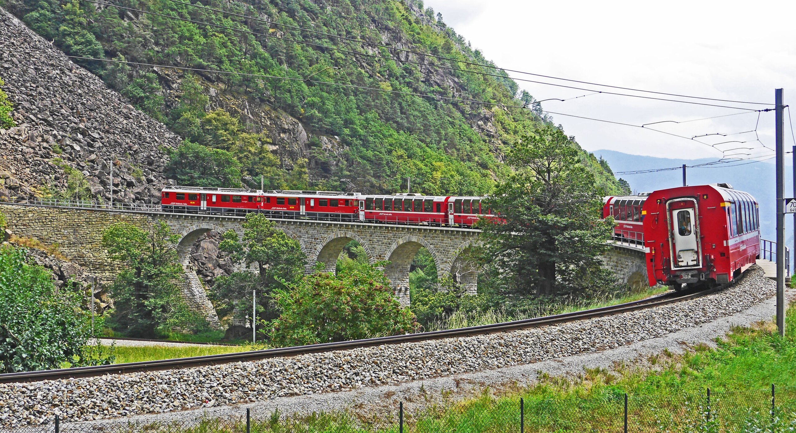 A red train of the Bernina Express in the Swiss Alps